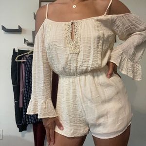 Whimsical beige romper with long sleeve.